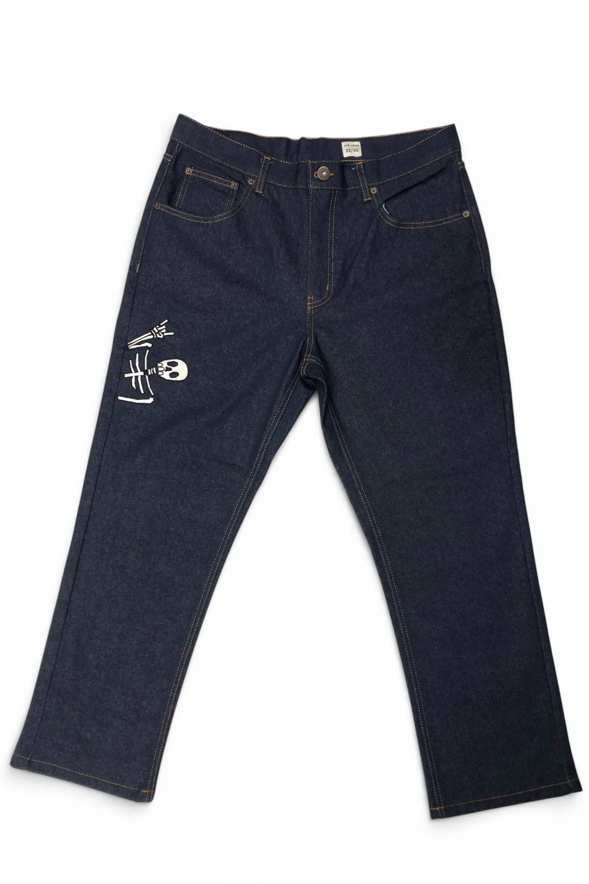 Front view of Common Saints dark indigo denim jeans with five-pocket styling, contrast stitching, and white skull graphic on the left thigh
