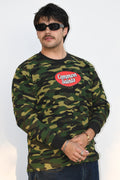Model wearing the Common Saints Woodland Camo Heavyweight Thermal with red oval chest logo and black ribbed trim, angled front view